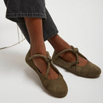 Brown ballet flats worn with dark jeans on a white background