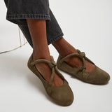 Brown ballet flats worn with dark jeans on a white background