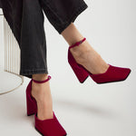 Red high-heeled shoes worn with black pants on a white background