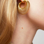 Gold hoop earring worn by a person with a neutral background