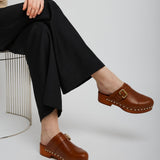 Person wearing brown clogs with a neutral background