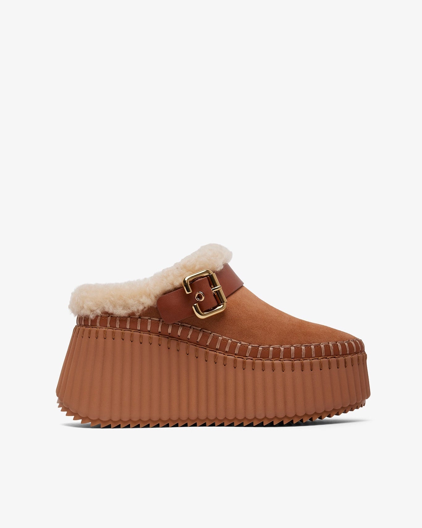 Brown platform clog shoe with fur trim and gold buckle on a white background