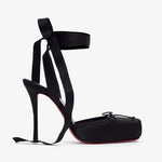 Black high-heeled shoes with ribbon straps on a white background