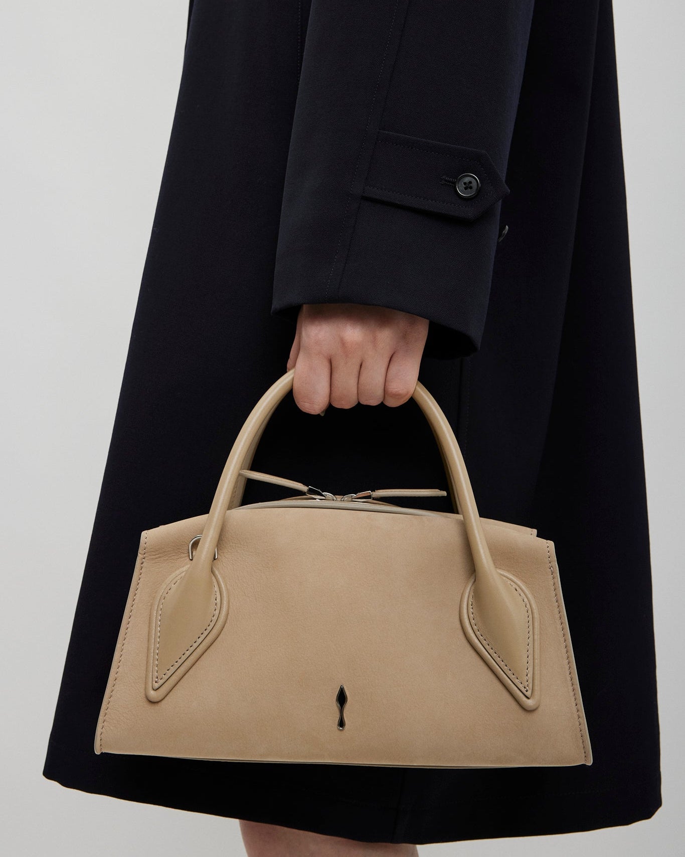 Person holding a beige handbag with a plain background