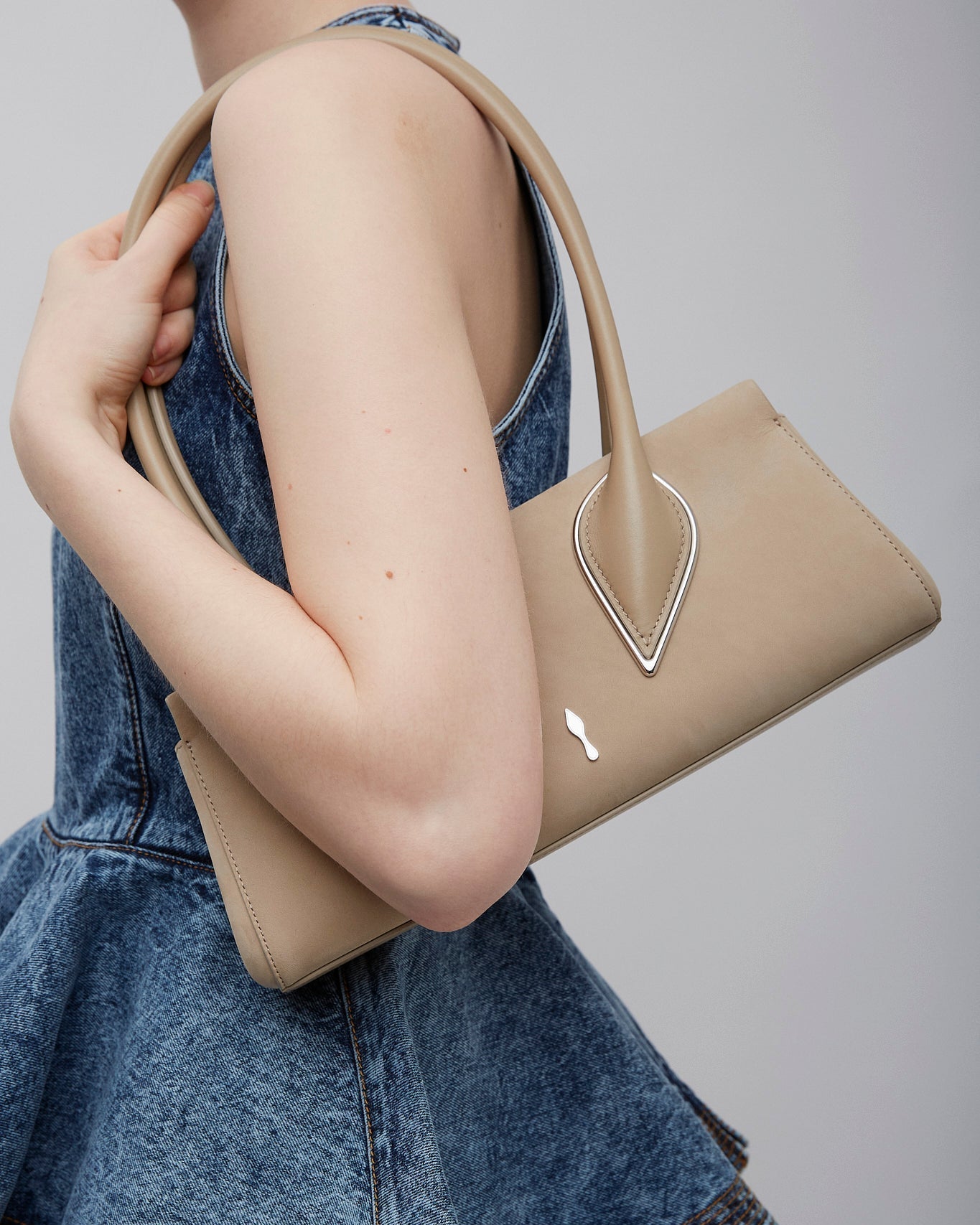 Person holding a beige handbag with a gray background