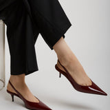 Person wearing black pants and red high heels on a light gray background