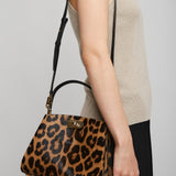 Person holding a leopard print handbag against a plain background