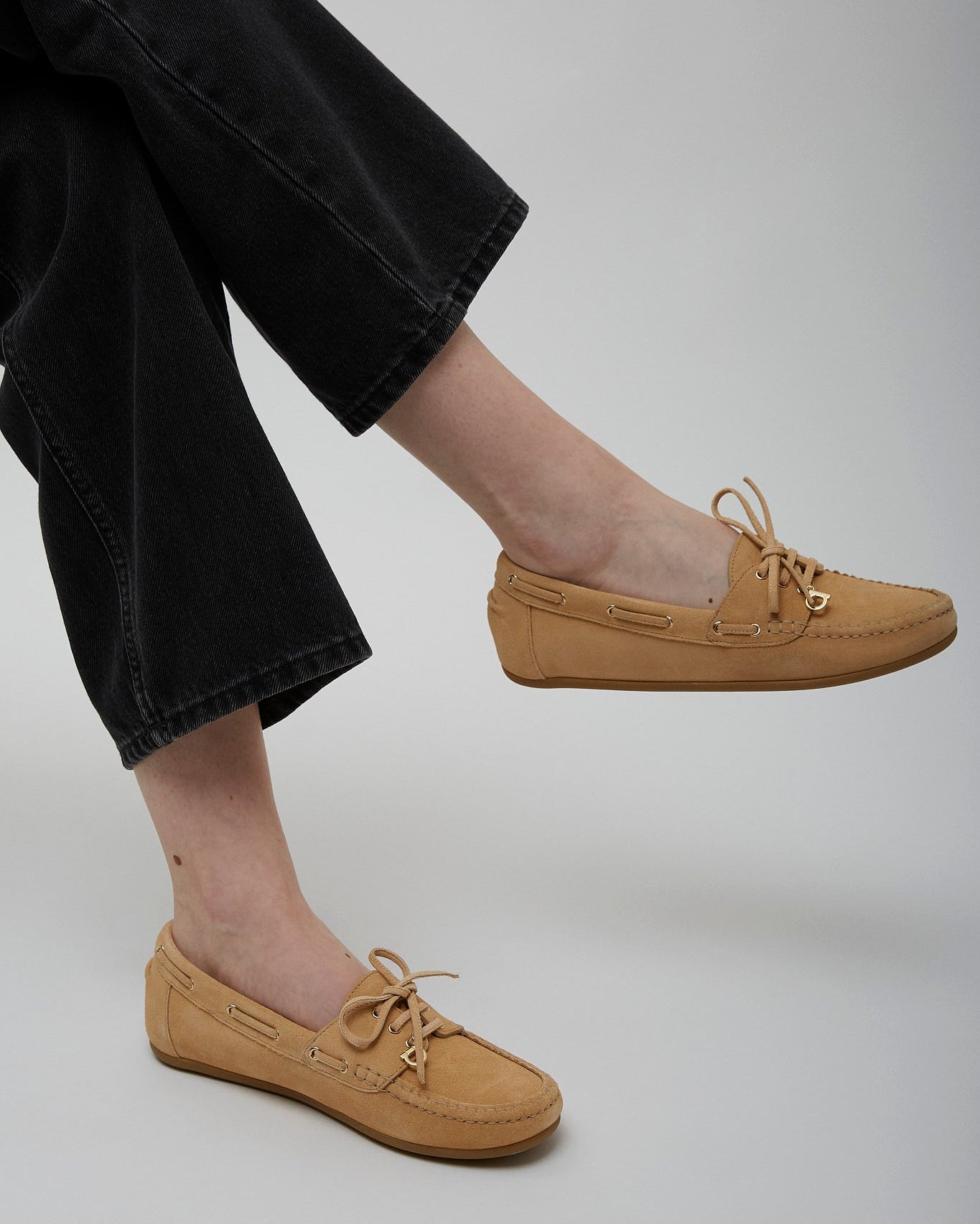 Tan shoes worn with black pants on a plain background