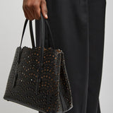 Person holding a black textured handbag against a plain background