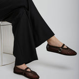 Person wearing black mesh sandals sitting on a chair with a plain background
