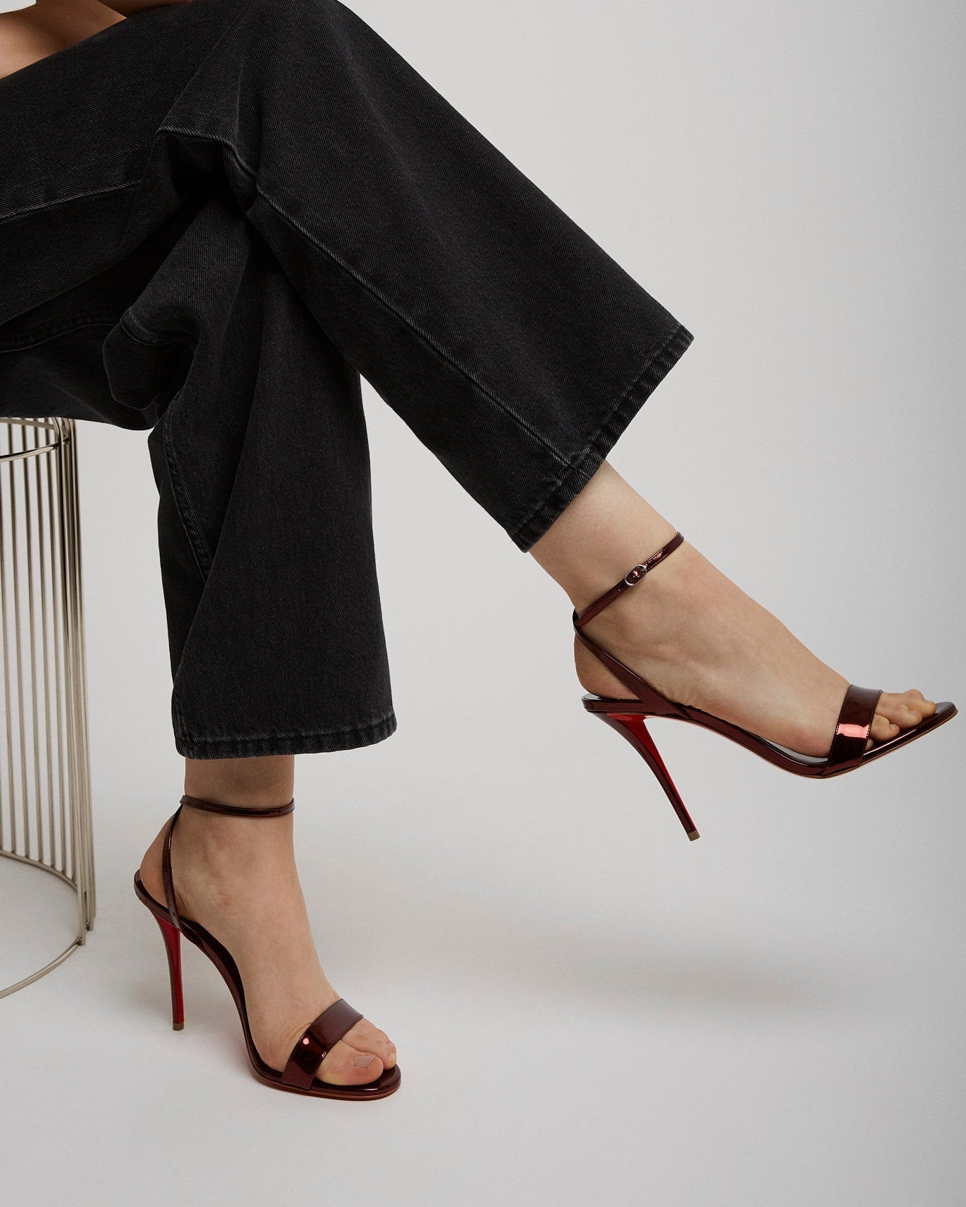 Person wearing black high-waisted jeans and red high-heeled shoes on a white background